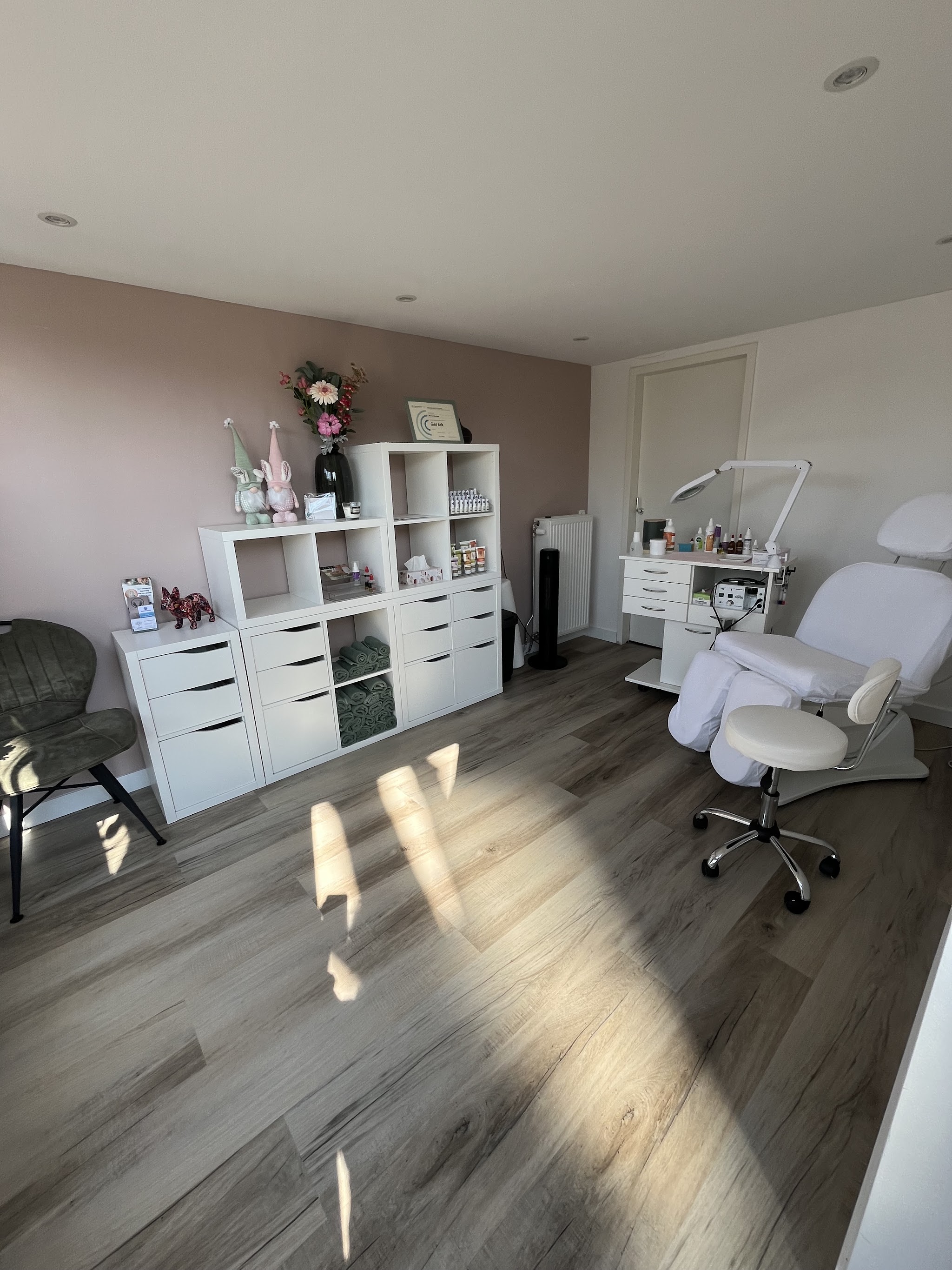 De lichte salon met behandelstoel en witte kast, met zon op de vloer